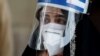 PAKISTAN - A woman wears a protective face shield and a protective face mask as she attends an event of mask distribution along a road, as the outbreak of the coronavirus disease (COVID-19) continues, in Karachi, Pakistan June 15, 2020