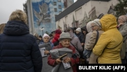 Banorët vendas marrin batanije gjatë shpërndarjejs së ndihmave në qendër të Hersonit më 17 nëntor 2022.