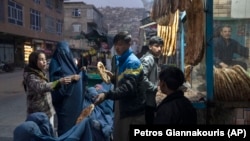 Një burrë u ndan ushqim disa njerëzve në Kabul, Afganistan.