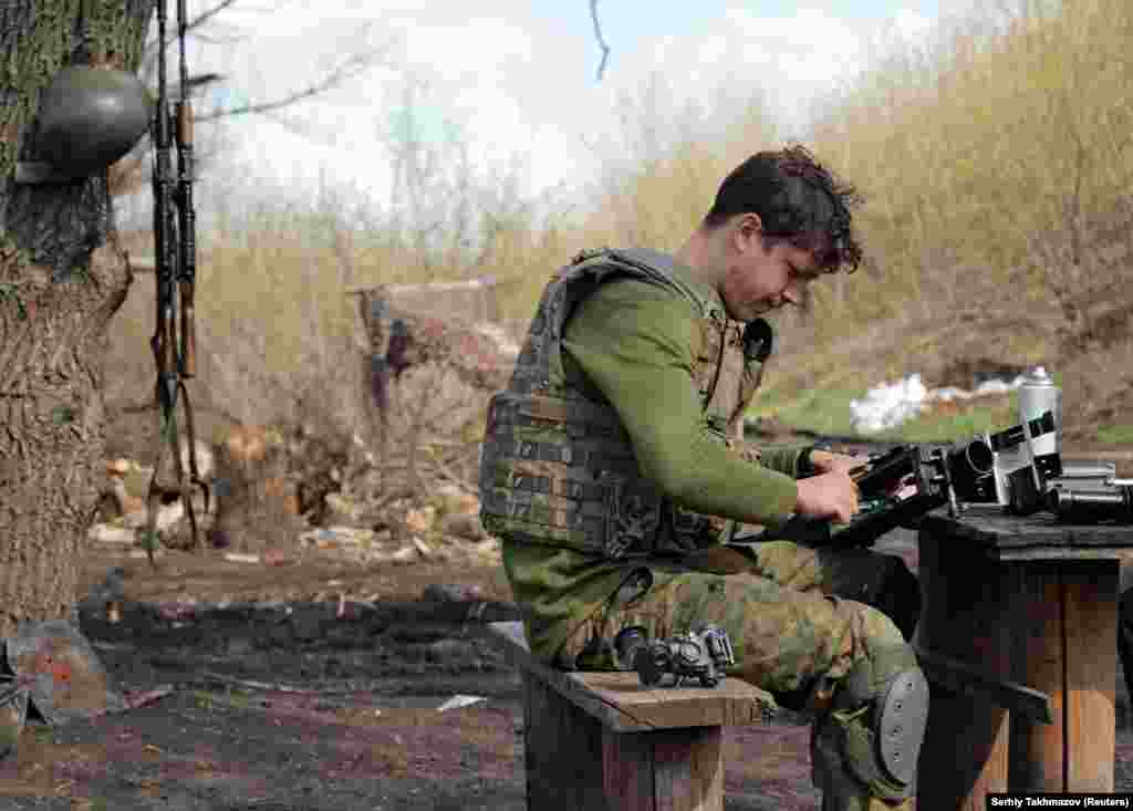 Припадник на украинските вооружени сили чисти оружје во близина на градот Доњецк.&nbsp;