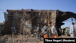 Жителите и полицијата стојат до куќите уништени во воздушен напад за време на борбите меѓу етиопските национални одбранбени сили и силите на Народниот ослободителен во регионот Афар, Етиопија, 25 февруари 2022 година. 