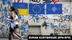 Две жени минават покрай графит с украинското знаме, знамето на ЕС и НАТО в Тбилиси, Грузия, 22 май 2023 г. Снимката е илюстративна.