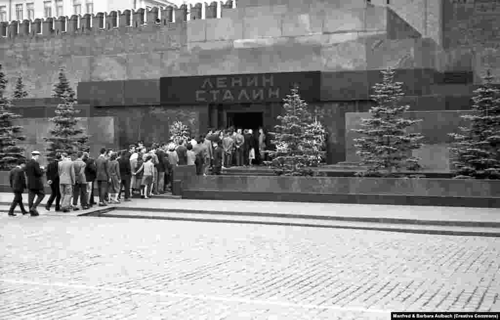 Посетители заходят в мавзолей Ленина и Сталина, август 1957 года. После смерти Иосифа Сталина в 1953 году его тело забальзамировали и разместили рядом с трупом Ленина. Над входом в мавзолей появилась вывеска с фамилиями двух советских диктаторов &nbsp;
