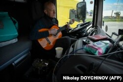 Shoferi Gediminas Gostautas luan me gitarë teksa pret në kufirin mes Bullgarisë dhe Rumanisë më 24 mars 2024.