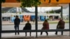 Qytetarë duke pritur në një stacion autobusësh përballë obeliskut të pavarësisë NEWBORN në Prishtinë, maj 2024.