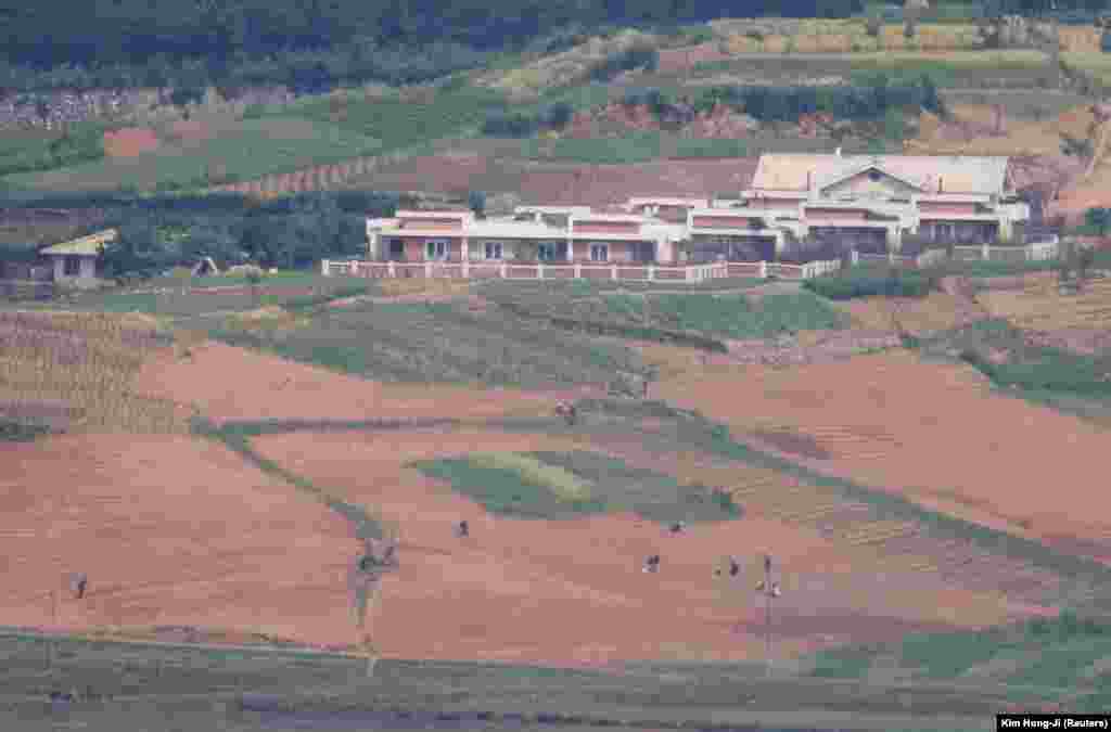 Njerëzit e Koresë së Veriut duke punuar në një fushë të mbjellë me oriz në fshatin propagandistik të Koresë së Veriut, Kaepoong. Fotografia është marrë nga Platforma e Vëzhgimit të Përbashkët, pranë zonës së çmilitarizuar që ndan dy Koretë në Paju, Koreja e Jugut, 31 maj 2023.