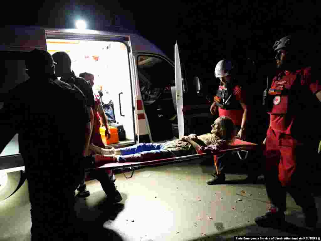 Paramedicii transportă o femeie rănită în timpul atacului cu rachete rusești din Nikolaev. &quot;Rușii au lovit centrul orașului. Un garaj și o clădire rezidențială cu trei etaje au luat foc.... În total, 18 persoane au fost rănite. Nouă dintre ele au fost spitalizate, inclusiv cinci copii, în timp ce două persoane au fost salvate de sub dărâmături. Este un miracol că am reușit să le salvăm&quot;, a declarat guvernatorul regional Vitali Kim.