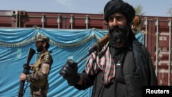 Luptători talibani stau de pază în timp ce oamenii așteaptă să primească saci de orez ca parte a ajutorului umanitar trimis de China, la un centru de distribuție din Kabul. (foto de arhivă)