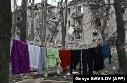 Rroba të varuar pranë një ndërtese banimi të shkatërruar në Avdivka.