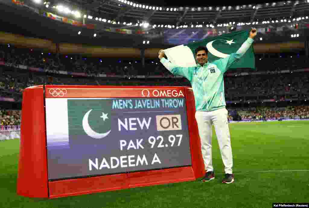 Arshad Nadeem iz Pakistana slavi nakon što je osvojio zlato dok stoji pored ekrana na kojem je prikazan njegov novi olimpijski rekord 8. avgusta.