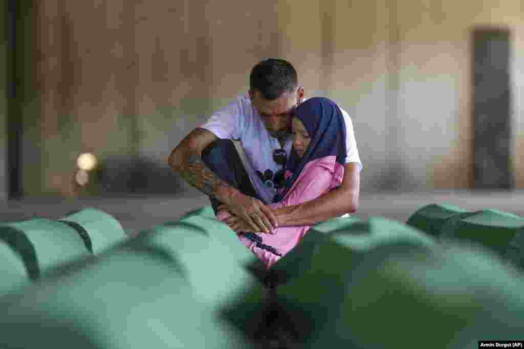 Egy férfi a lányával az édesapja maradványait tartalmazó koporsó mellett a Srebrenica-Potočari Emlékközpontban július 10-én, egy nappal a majdnem három évtizedet késő temetés előtt