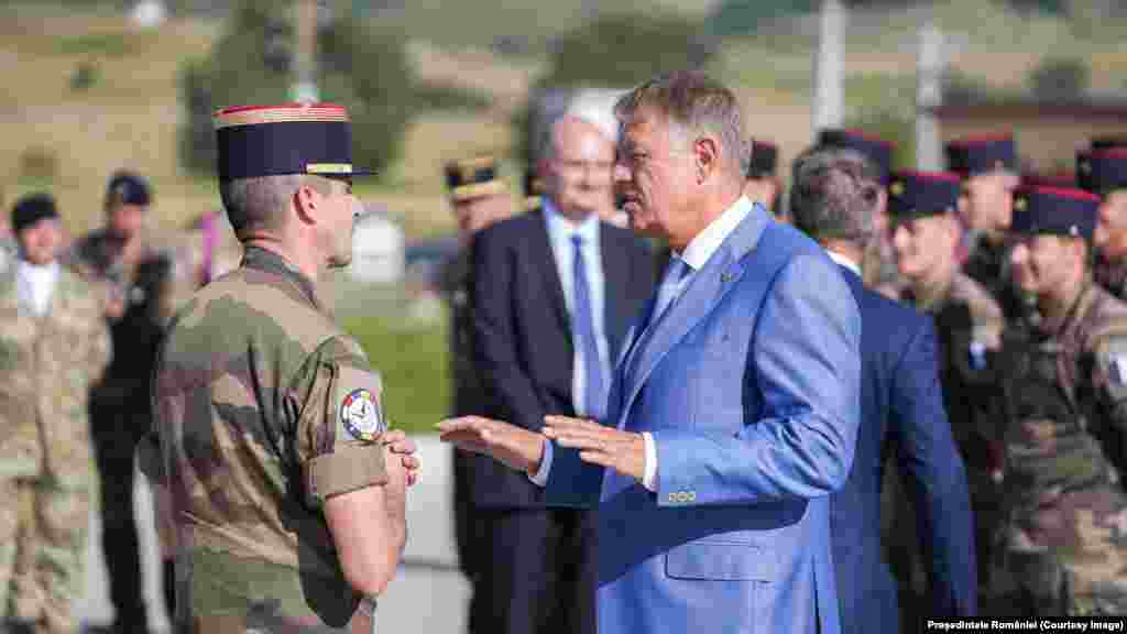 Președintele României, Klaus Iohannis, discută cu un comandant NATO la o bază din Cincu, în centrul României, la 5 septembrie. Iohannis a declarat reporterilor, în timp ce vizita baza militară NATO: &bdquo;Pot să vă spun că nicio parte a vreunei drone sau altă componentă a vreunui alt dispozitiv nu a aterizat în România. Avem un control total asupra teritoriului nostru&quot;, adăugând: &bdquo;Am verificat absolut totul și vreau să liniștesc populația&rdquo;.