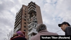 Локални жители стојат пред станбена зграда погодена од напад на руски дрон во Харкив на 4 април.