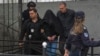 Suspectul în cazul împușcăturilor, cu capul acoperit de o haină, este escortat de poliție în fața școlii „Vladislav Ribnikar” din Belgrad, pe 3 mai.