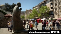 Turistët shijojnë rrezet e diellit në Shkup pranë një prej 280 statujave të tij të vendosura gjithandej nëpër kryeqytetin maqedonas.