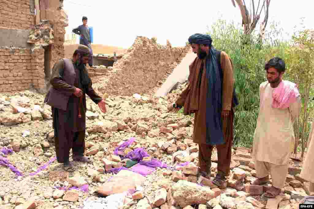 Njerëzit qëndrojnë pranë rrënojave të një ndërtese të shembur në Kandahar, më 22 korrik. &nbsp;