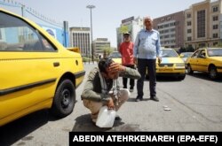 Egy teheráni taxisofőr vizet fröcsköl az arcára egy forró, napsütéses napon az iráni fővárosban a hónap elején