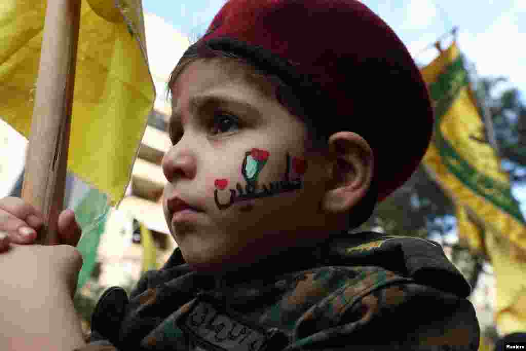 Egy kisfiú zászlót tart egy Hezbollah-támogatói tüntetésen&nbsp;Bejrút déli külvárosában, Libanonban 2023. október 18-án, egy nappal azután, hogy&nbsp;több száz palesztin halt meg a gázai al-Ahli kórházban történt robbanásban. A tragédiáért az izraeli és palesztin tisztviselők egymást tartják felelősnek