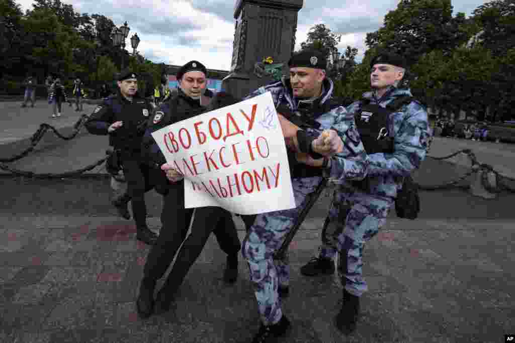 Полицаец приведува демонстрант со постер на кој пишува: „Слобода за Алексеј Навални“ на плоштадот Пушкинскаја во Москва, на одвележувањето на роденденот на затворениот руски опозииски активист.