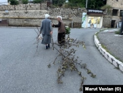Femei în vârstă în Stepanakert în seara zilei de 17 iulie. Una dintre femei târăște o creangă pe care o va folosi ca lemn de foc pentru a găti.