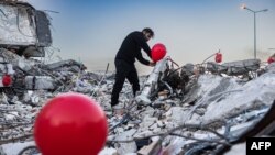 Мъж закача балони на отломките на срутена сграда в Антаркия като символ на жертвите на земетресението. Снмиката е от 21 февруари