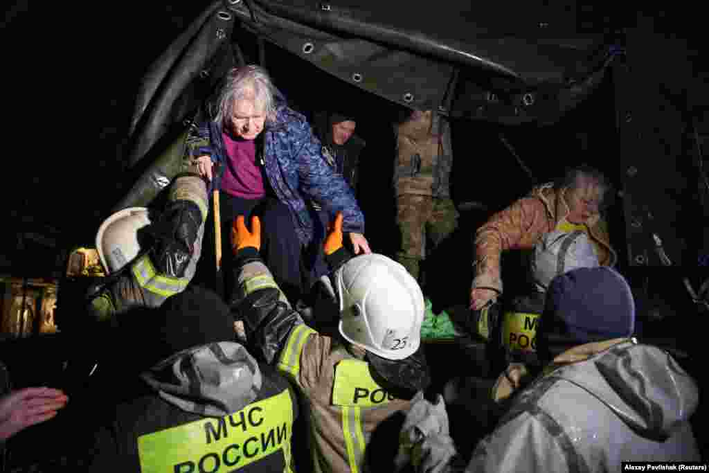 Localnicii sinistrați sunt ajutați de salvatori să coboare dintr-un camion după o evacuare de urgență de pe o stradă inundată din orașul Evpatoria din Crimeea, pe 26 noiembrie. Oleg Kriucikov, oficial rus instalat în regiunea pe care Moscova a anexat-o de la Ucraina în 2014, a declarat că o persoană a murit în urma inundațiilor. &nbsp;