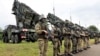 Militari germani aliniați în spatele unor baterii Patriot, în timpul unei vizite a președintelui ucrainean Volodimir Zelenski la un poligon din Germania, în 2024. Ucraina are nevoie de sistemele americane de apărare antiaeriană pentru a-și proteja orașele de atacurile rusești. 