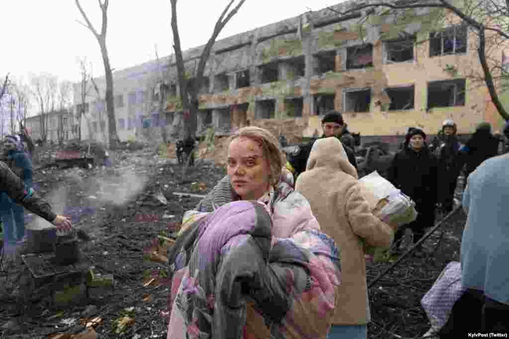 Njerëz duke lëvizur pranë objektit të spitalit të lindjes në Mariupol, pas sulmit ajror të kryer nga Rusia, më 9 mars.