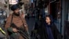 Një militant taliban i bën roje një gruaje në Kabul. Dhjetor 2022.
