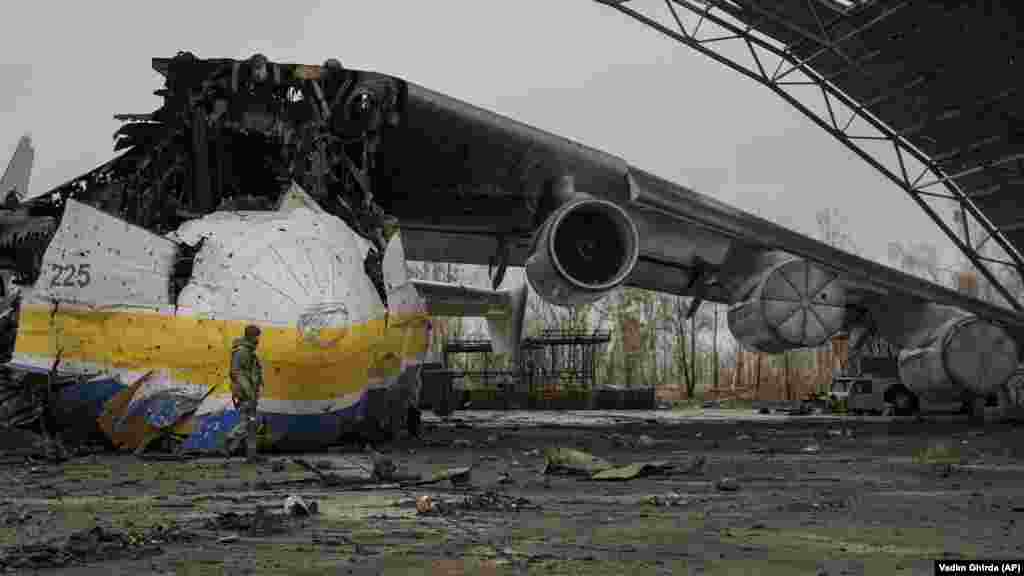 Украински војник поминува покрај остатоците од транспортниот авион Антонов Ан-225 Мрија на 2 април 2022 година. Мрија, кој беше најголемиот авион на светот, беше уништен од руски напад на 27 февруари за време на борбите на аеродромот Антонов во Хостомел. Мрија, што значи „сон“ или „инспирација“, беше сакан од авијациските ентузијасти ширум светот.