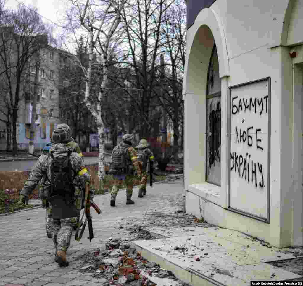 Украински војници поминуваат покрај графити на кои пишува &bdquo;Бахмут ја сака Украина&ldquo; на 18 декември. И Русија и Украина во моментов внесуваат луѓе и материјал во борбата за Бахмут, град во регионот Донбас во источна Украина кој има релативно мало воено значење, но стана жестоко оспоруван симбол за двете страни.