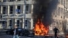 Мужчины бегут с места удара российских военных, когда горят автомобили в центре Киева, Украина. 10 октября 2022 года. 