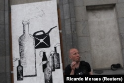 Artisti Zinkivskiy qëndron pranë muralit të tij ku shkruan: "Mikpritje djallëzore".