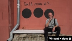 Hamlet Zinkivsky, i ulur pranë një murali që ka krijuar në Harkiv. Në të shkruan: Po! Ose ndoshta jo?"