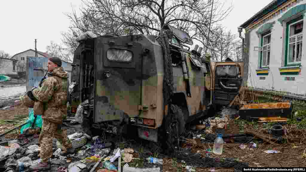 Украински войник стои близо до изоставен руски брониран автомобил.