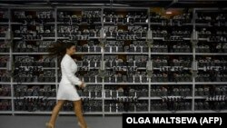 Një grua kalon pranë pajisjeve për prodhimin e bitcoin-it gjatë një prezantimi të qendrës më të madhe të kriptomonedhave në Rusi, Kriptoyunivers, më 2018.