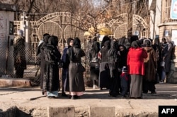 Studente al căror acces la cursuri a fost interzis de talibani stau lângă o universitate din Kabul, în decembrie.
