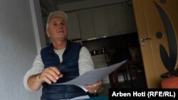 Ibrahim Hetemi, përdorues i karrocës, vëzhgon rrugën nga ballkoni i banesës së tij.
