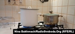 Valentyna duke ngrohur dy tenxhere me ujë pasi avulli që prodhojnë e ndihmon të ngroh pak kuzhinën e saj.