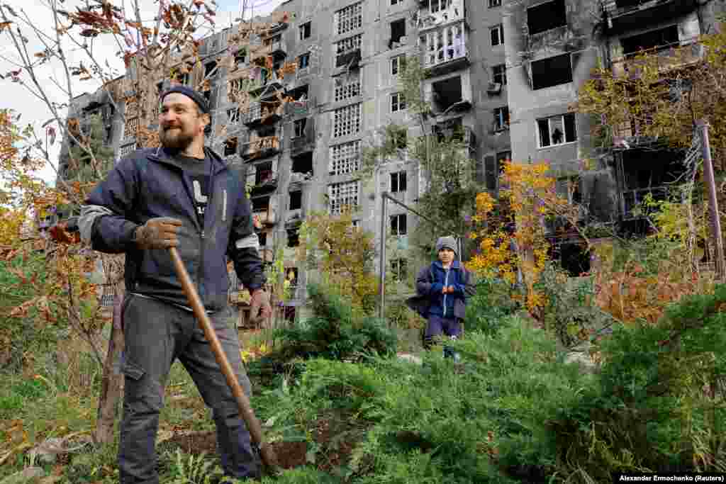 Жител на Мариупол и неговиот млад внук работат во дворот на оштетена зграда на 29 октомври. Мариупол беше заземен од руските сили во мај, откако неколкумесечните борби оставија околу 90 отсто од зградите во градот оштетени или уништени. Илјадници луѓе загинаа во она што стана познато како опсада на Мариупол.