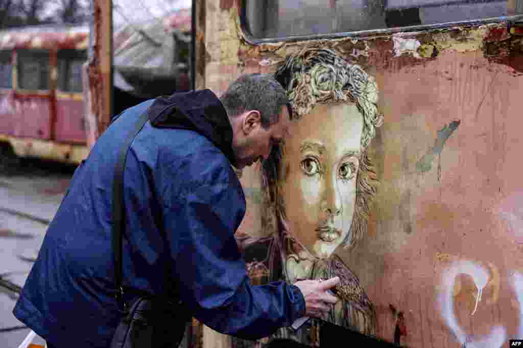 Artistul francez Christian Guemy pictează în apropierea unei stații de metrou, grav avariată de un atac rusesc în Kiev, în aprilie.