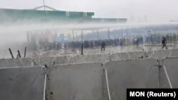 A lengyel védelmi minisztérium videójának képernyőképén a lengyel biztonságiak vízágyút vetnek be a belarusz határt átlépni próbáló migránsok ellen a Kuźnica–Bruzgi átkelőnél 2021. november 16-án
