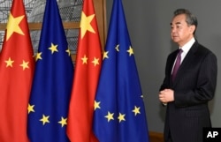 Kineski ministar inostranih poslova Vang Ji stoji pored zastava EU i Kine dok čeka dolazak predsjednika Evropskog vijeća Charlesa Michela u Briselu 2019.
