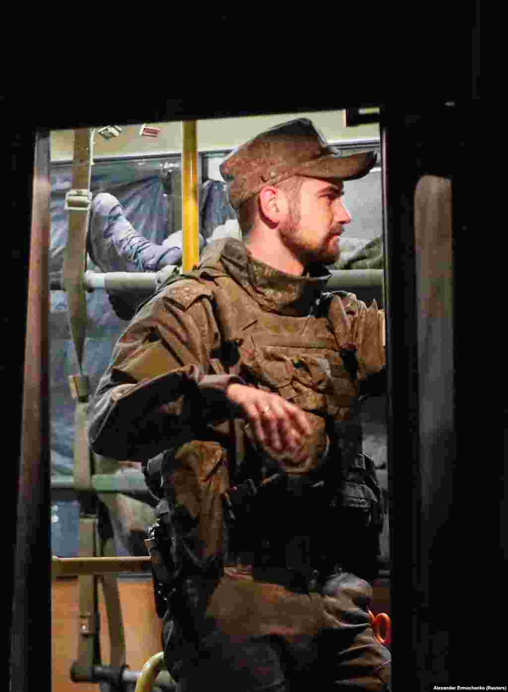 Un luptător separatist păzește un autobuz care transportă soldați ucraineni răniți de la Mariupol.
