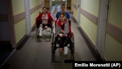 Urmat de mama lor Natașa, Iarik Stepanenko, de 11 ani, împinge scaunul rulant în care se află sora sa geamănă Iana, Liov, 12 mai. Ei au fost răniți după ce o rachetă rusească a lovit gara din orașul Kramatorsk, estul Ucrainei, pe 8 aprilie.