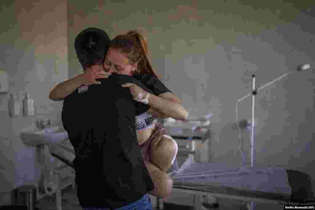 Оксана Баладина (23) во рацете на нејзиниот сопруг Виктор во болница во Лавов на 13 мај 2022 година. Оксана ги загуби двете нозе и четирите прсти на левата рака кога граната експлодираше во близина на нејзината куќа. &bdquo;Имаше експлозија. Чувствував како моите нозе да паѓаат во празнина веднаш потоа. Се обидував да погледнам наоколу и видов дека веќе немам нозе - само коски, месо и крв&ldquo;, се сеќава таа.