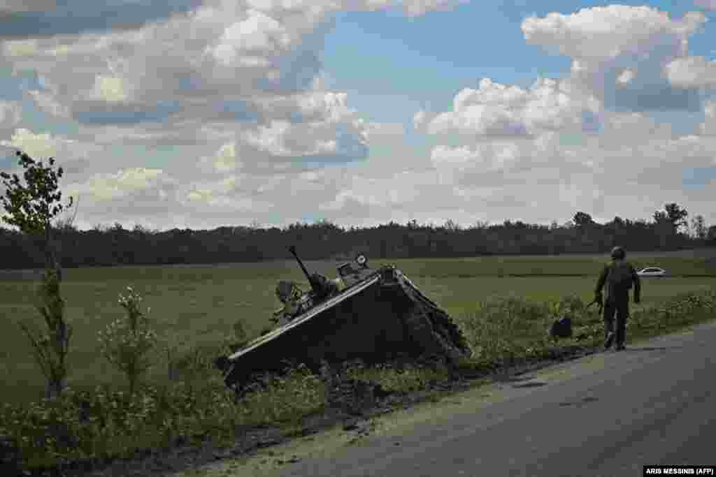 A Ukrainian serviceman passes a damaged Ukrainian armored vehicle.