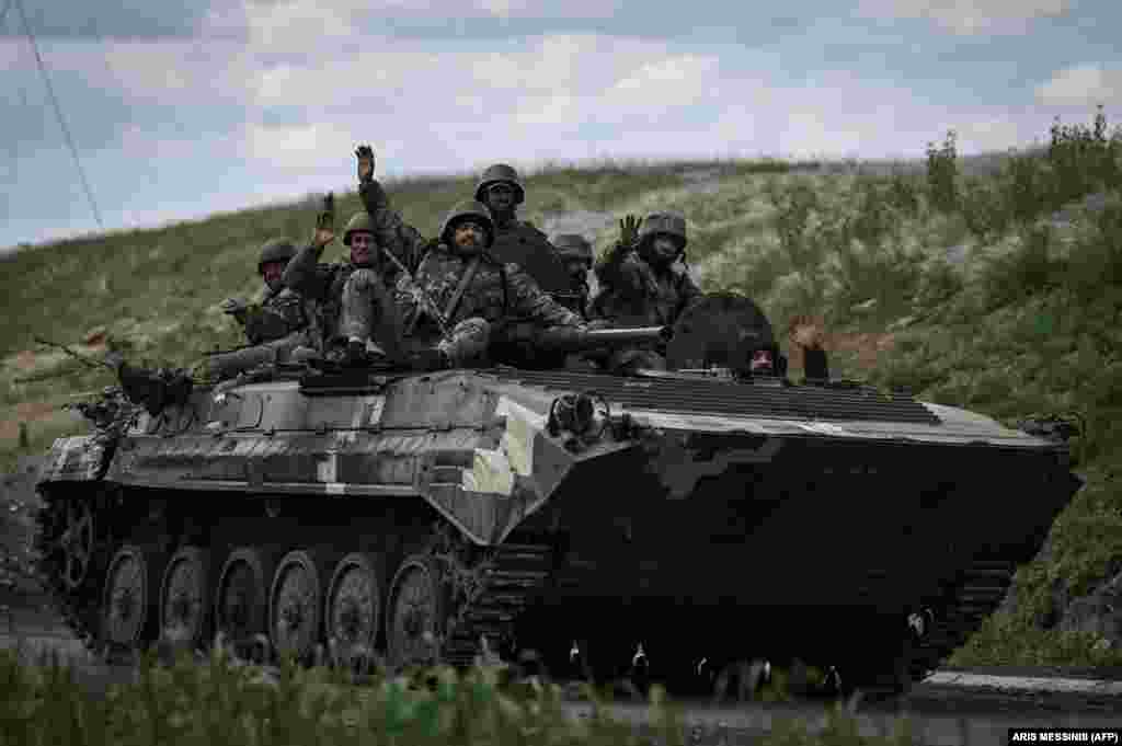 Ukrainian soldiers wave as they head toward the front line near Lysychansk.