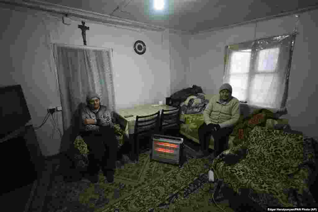 Două femei în vârstă se încălzesc lângă un radiator în Stepanakert. 