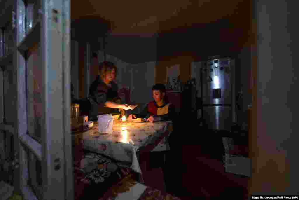 O femeie și fiul ei iau cina la lumina lumânărilor în casa lor din Stepanakert. 